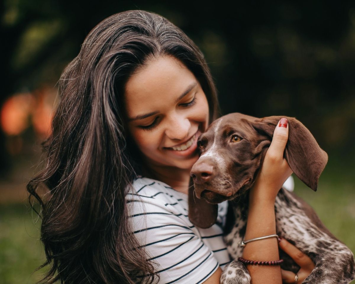 a woman is holding her dog in the grass